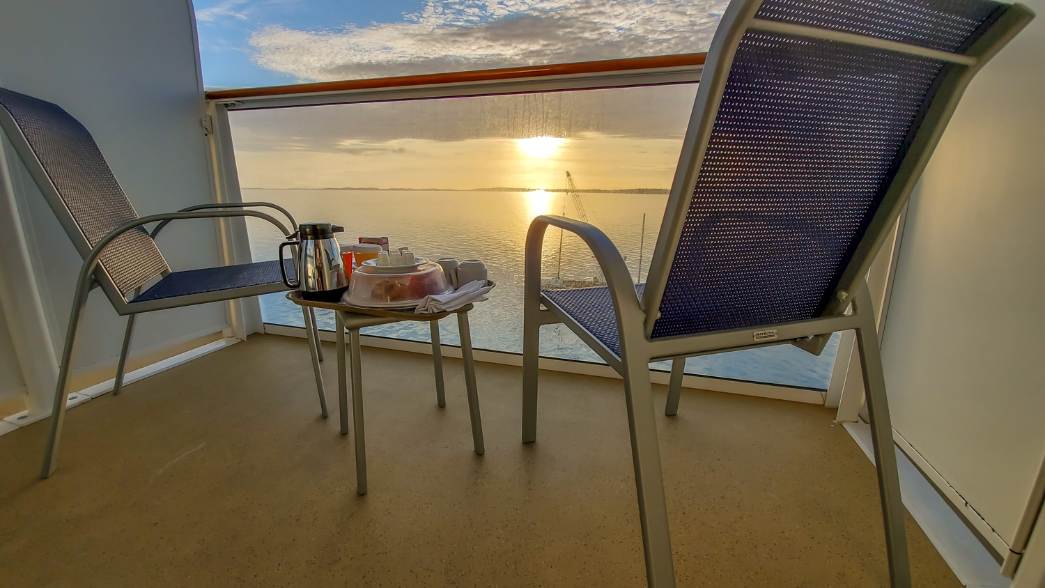 Balcón del Norwegian Escape con servicio de desayuno en la habitación en bandeja con salida del sol